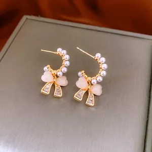 Elegant bow pearl earrings with zircon stones and heart charm on dark orange satin