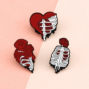 Cartoon enamel heart and ribcage brooches with red roses on pink background