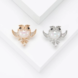 Elegant gold and silver owl brooches with pearls and rhinestones on a white base