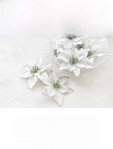Detailed view of silver glittered artificial poinsettia flower on white plush background