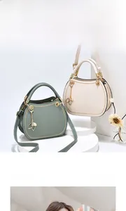 Detail of elegant semi-circular leather handbags in sage green and cream with metal charms