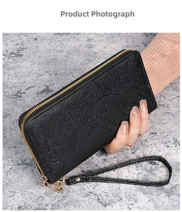 Detail of floral embossed texture on black long leather wallet with gold zipper and strap