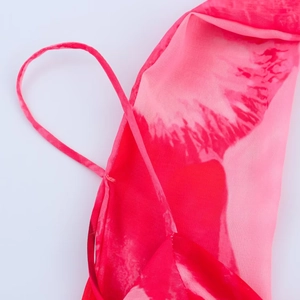 Detail von rot-pinkem Batikmuster auf transparentem Stoff mit zarten dünnen Schultergurten