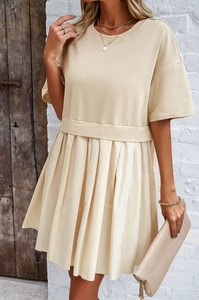 Dettaglio di elegante abito beige a maniche corte con gonna a pieghe e vita stretta