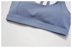 Close-up of misty blue sports bra featuring wide hem support and premium stitching details