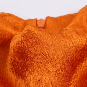 Detailed macro view of orange textured satin fabric with a matching zipper closure