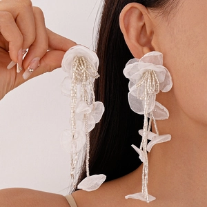 Close-up of white lace flower earrings with silver seed bead tassels on female model