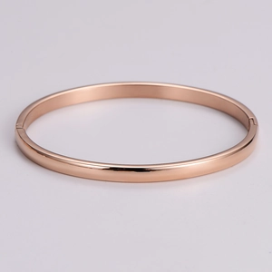 Macro detail of rose gold minimalist bracelet with polished finish and side hinge closure