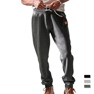 Men's loose drawstring joggers with elastic cuffs and decorative leather patch details
