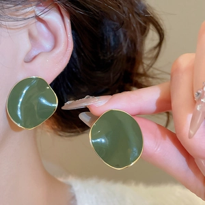 Close-up of vintage dark green enamel earrings with gold edges on model's ear