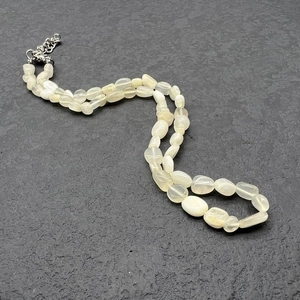 Close-up of irregular natural quartz beads with stainless steel clasp on rock surface
