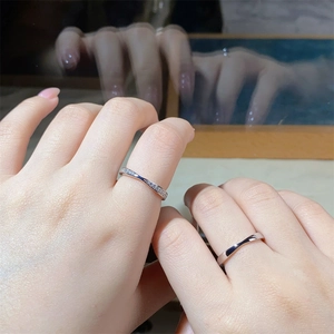 Close-up of a silver Mobius-style couple's ring set featuring a petite zircon band