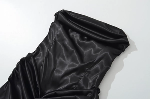 Détail d'une élégante robe en satin noir avec un design plissé froncé luxueux