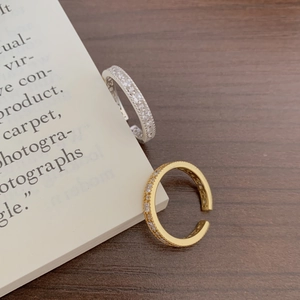Detailed view of gold and silver open rings with pavé zircon on vintage book pages