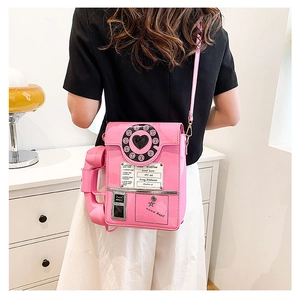 Rear view of a model wearing a pink vintage telephone shaped crossbody bag in high gloss