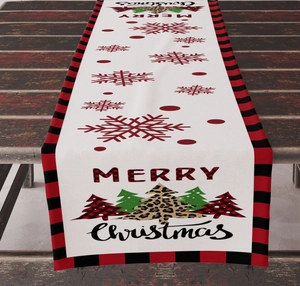 Detail of Christmas table runner with red snowflake and Merry Christmas print on wooden desk