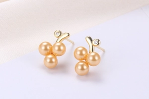 Detailed view of grape cluster earrings with orange pearls and sparkling cubic zirconia