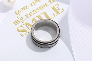 Macro detail of brushed stainless steel ring featuring a central groove on a white background
