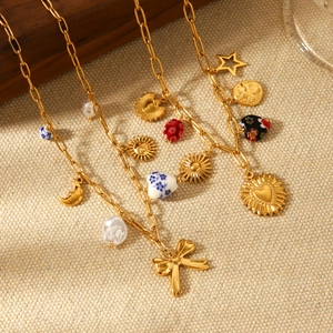 Vintage gold layered necklace with pearl, heart, and butterfly charms on beige fabric
