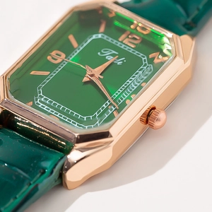 Macro detail of rectangle rose gold watch case with emerald green dial and leather strap
