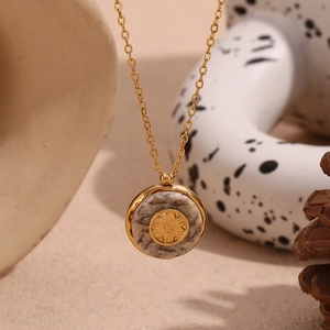 Close-up of 18K gold-plated necklace with marble stone pendant and sunburst flower detail