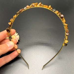 Detail of handmade gold metal headband with natural amber crystal stones being held by hand