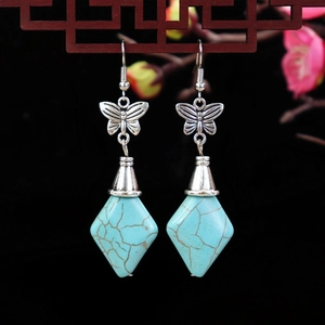 Detailed macro of vintage silver earrings featuring butterfly stud and blue turquoise stones