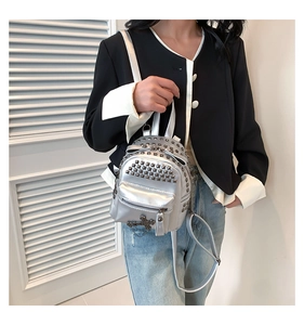 Close-up of silver punk backpack featuring metal rivets and decorative cross pendant