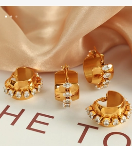 Detailed view of 18K gold plated C-shape earrings with pave crystals on silk background