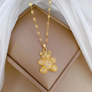 Luxurious gold teddy bear pendant necklace with sparkling zircons on a white silk background