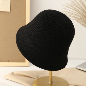 Gros plan d'un bob en tricot noir montrant la texture côtelée verticale sur support doré