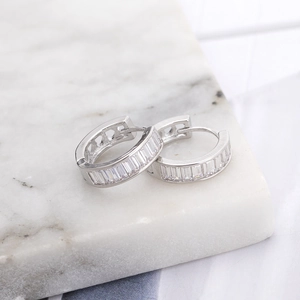 Silver hoop earrings with baguette-cut cubic zirconia on elegant white marble base