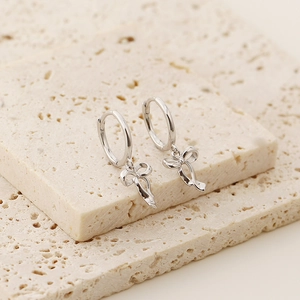Detailed close-up of S925 silver bow ribbon earrings on decorative stones with soft lighting