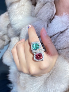 Detail of emerald cut green and pink dual stone ring on luxury white fur background