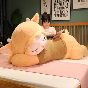 Large plush sheep toy in orange wearing a brown knit sweater shown on a cozy bed