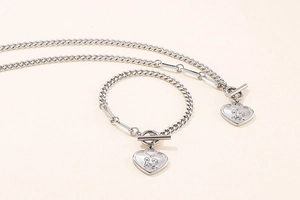 Close-up of silver Cuban chain set with heart pendants featuring boy and girl engraving