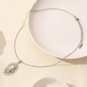 Macro shot of silver sunburst necklace with oval gemstone and lobster clasp detail