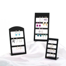 Three sizes of black acrylic jewelry stands for earrings on white silk background