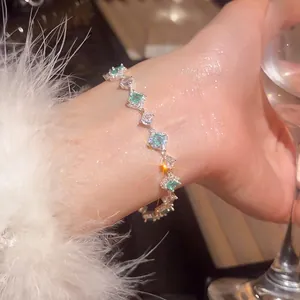 Elegant silver bracelet with green zircon and white diamonds on a female wrist