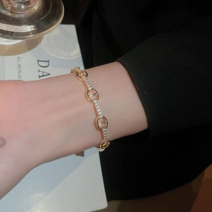 Detail of gold plated oval link bracelet with sparkling cubic zirconia on female wrist