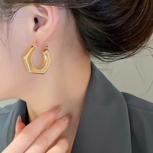 Close-up of golden hexagonal geometric hoop earring on a model for daily wear