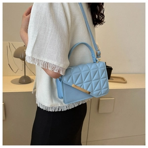 Detail shot of the blue quilted PU leather handbag with elegant gold metal rod accent