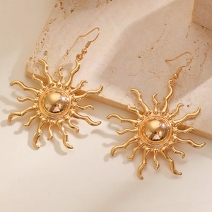 Close-up of golden sun-shaped pendant earrings with radiant sunbeam design on stone base