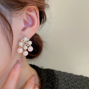 Close-up of gold-plated tassel earrings with pink pearls and square zircon on model
