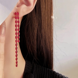 Detail shot of long tassel earrings with red cubic zirconias and gold plating on model
