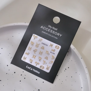 Detailed macro shot of gold constellation nail charms with rhinestones on a display card