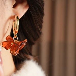 Close-up of vintage amber resin flower petal earring with gold circular hoop on model