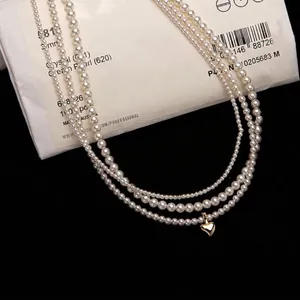 Triple layer freshwater pearl choker necklace featuring a golden heart pendant and high luster