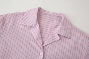 Gros plan détaillé du col, de la patte de boutonnage et des boutons d'un ensemble rayé rose
