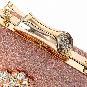 Macro-opname van een roségouden glitteravondtas met metalen sluiting bezet met kristallen